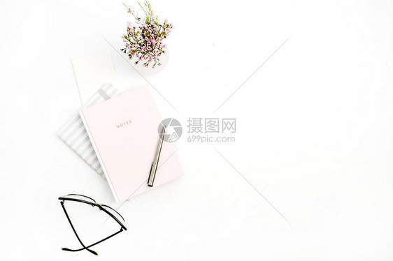 白色背景的带笔记本眼镜钢笔和野花束的现代女最低家庭办公桌FlatLap图片