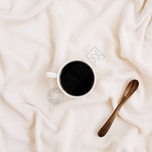 咖啡杯和木勺放在米色纺织品背景上图片