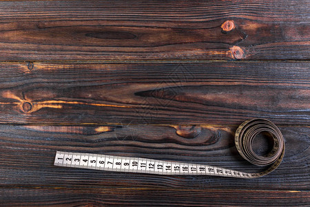 在木桌背景上贴近裁缝的测量磁带白色测量磁图片