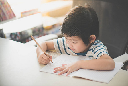 小亚洲小孩用铅笔在书桌上图片