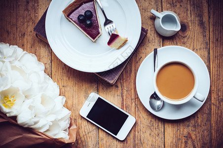 郁金香咖啡加牛奶芝士蛋糕和智能手机图片
