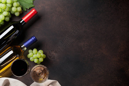 石头桌上的酒瓶和葡萄您文字的顶端图片