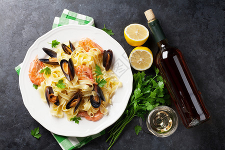 石桌上有海鲜和白葡萄酒的意大利面贻贝图片