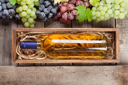 木制桌上的酒瓶和葡萄顶视图图片