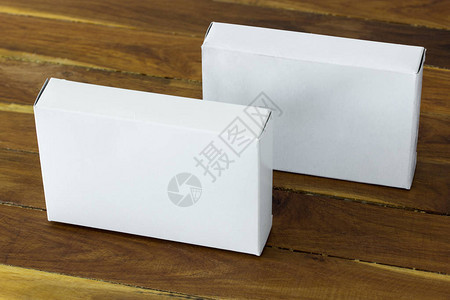 深色木桌上的空白色纸板包装盒模型图片