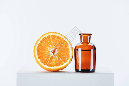 一瓶天然草本精油和在白色立方体上切橙子图片