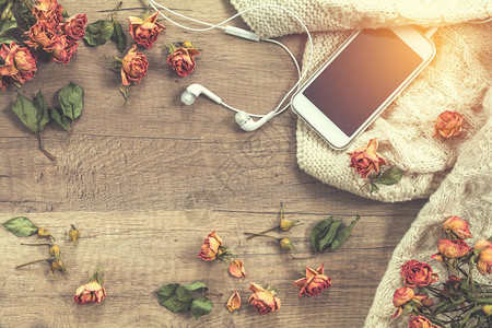 白色编织羊毛干玫瑰鲜花手机和耳机美丽的浪漫的外表背景图片