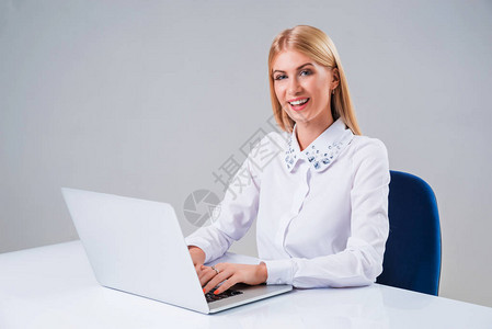 年轻女商人在笔记本电脑上工作她很高兴图片