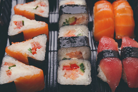 寿司马基和卷盘在黑外卖盒海鲜背景上安图片