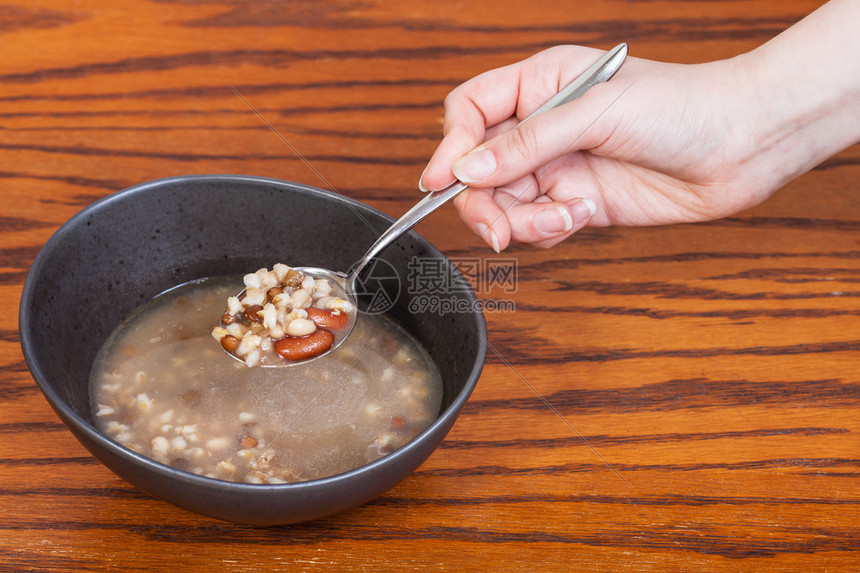 手拿着勺子和豆汤在木图片