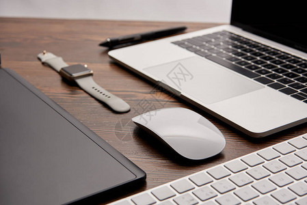 用无线鼠标和键盘智能手表和图形平板坐在木制桌上的笔记本电图片