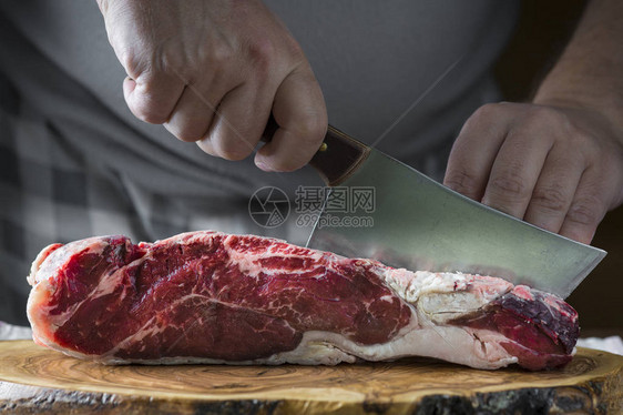 屠夫用切肉刀在板上切一块肉图片