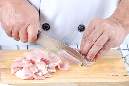 关闭厨师在切菜板上切猪肉用于烹饪图片