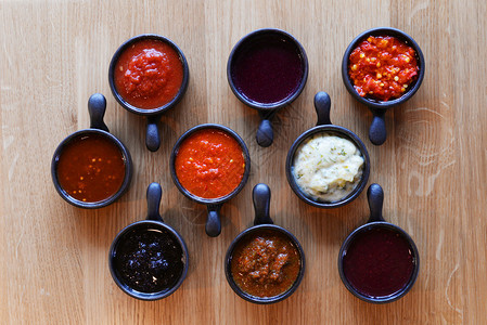 木桌上的黑色杯子里有各种不同的酱汁图片素材
