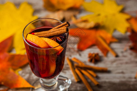 热红酒在秋天的背景上玻璃杯中的橙色肉桂红葡萄酒精秋叶黄红色在木图片