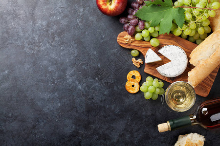 石桌上的白葡萄酒葡萄面包和奶酪带复制空间的顶视图图片