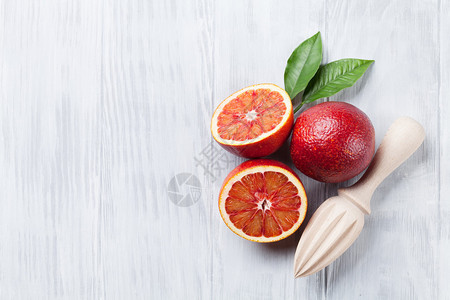 木制桌上新鲜成熟的红橙子和果汁机图片