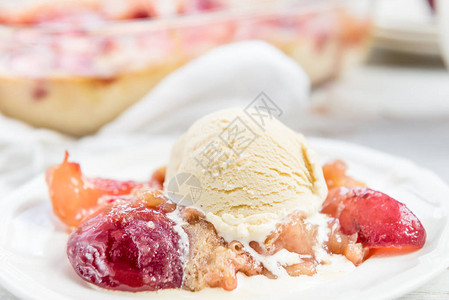 一块自制油桃派配香草冰淇淋在白盘上图片