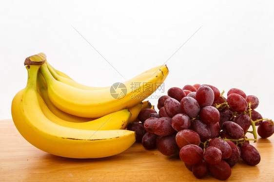 白色背景桌子上的香蕉和葡萄图片