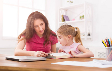 妈帮女儿做作业小女孩在家和妈一起学习阅读母联合活动和兴趣教育和图片