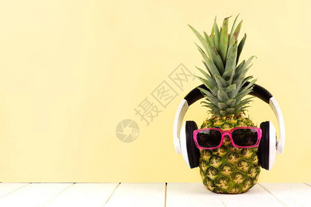 在黄色背景下戴墨镜和耳机的歇斯底里菠萝图片