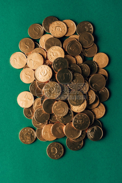 绿色桌上金质硬币堆积的顶部视图图片