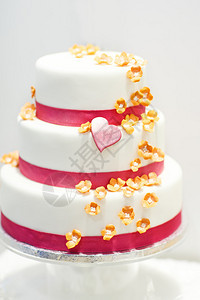 用粉红色玫瑰花朵和心形装饰的婚礼蛋糕图片