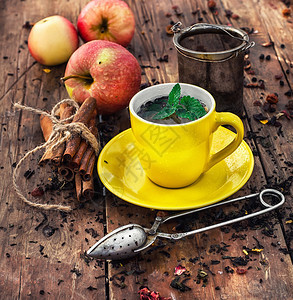 在散落着茶叶的木质背景上一杯冲泡的凉茶图片