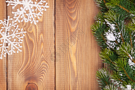 质朴的木板上有雪和花装饰的圣诞杉树图片