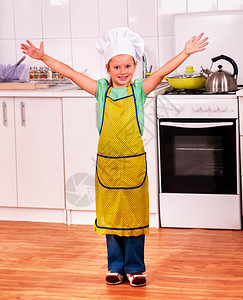 孩子戴着帽子和围裙在厨房做饭童年概念图片
