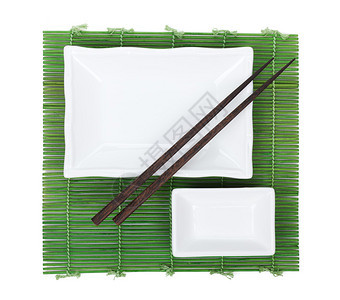 竹席上的筷子和餐具在白色背景下被隔离图片