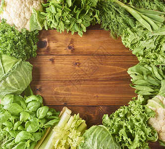 木制背景上的各种类型的沙拉叶和卷心菜生菜芝麻菜楣红硬生菜菠菜为您的文本设计带有空间的图片