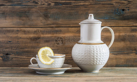 杯绿色茶加柠檬片和木本的茶壶图片