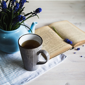 一杯蓝色花朵的茶和一本木制背景的书复古图片
