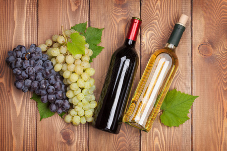 木桌上的红白葡萄酒瓶和葡萄串图片