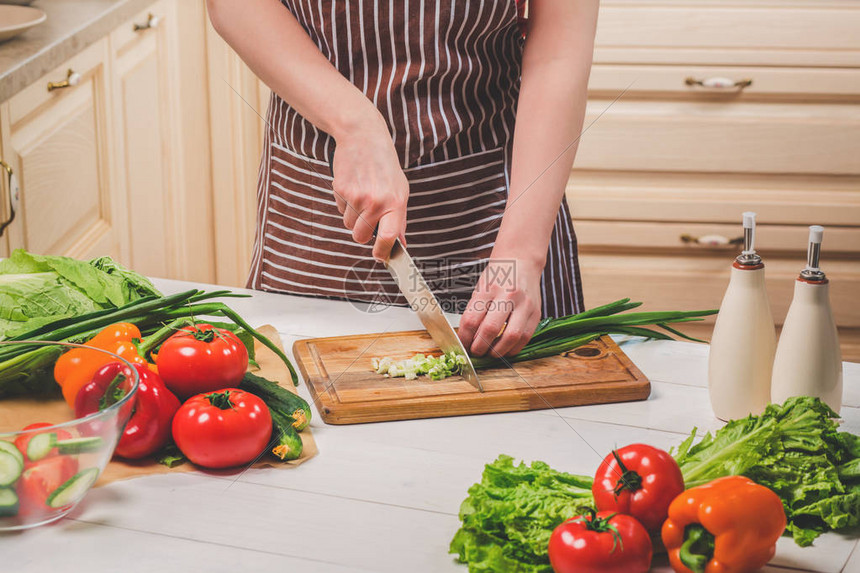 年轻女子在家里的厨房做饭健康食品饮食节食的概念健康的生活方式在家做饭准备食物一个女人用刀图片