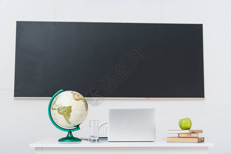 笔记本电脑放在黑板前的教室里图片