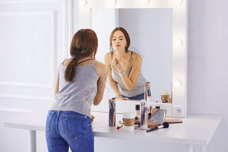 神奇的年轻女人在镜子前化妆图片