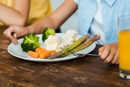 近距离部分观察儿童在吃健康蔬菜时持有叉子图片