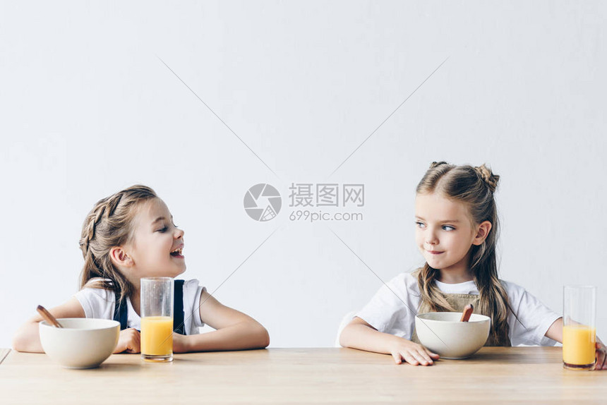 可爱的笑着微笑的女学生们吃麦片和橙汁图片