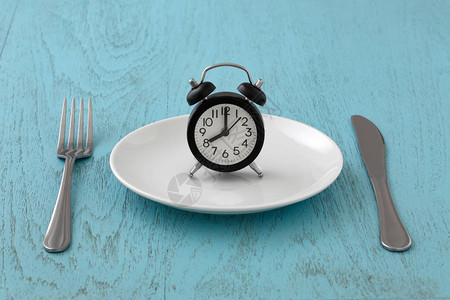 白板上刻有叉和刀的钟间断禁食饭食计划蓝桌图片