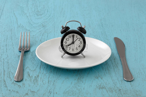 白板上刻有叉和刀的钟间断禁食饭食计划蓝桌图片