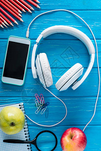 头耳机带空白屏幕的智能手机蓝木背景的苹果图片