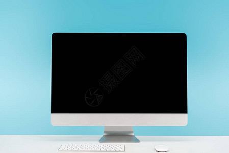 蓝色背景的白桌上带有计算机监视器键盘和计算机鼠标的图片
