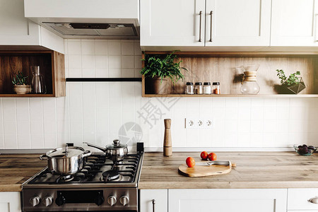 在斯堪的纳维亚风格的现代厨房烹饪时尚的厨房内部配有现代家具和不锈钢器具木台面钢炉木板刀和背景图片