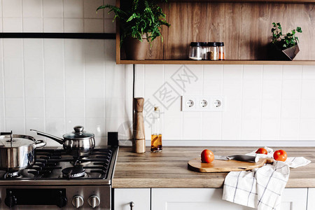 在斯堪的纳维亚风格的现代厨房烹饪时尚的厨房内部配有现代家具和不锈钢器具木台面钢炉木板刀和图片