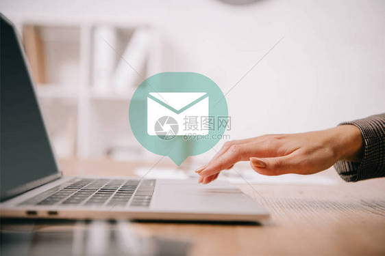 商业妇女用电子邮件图标在工作场所笔记本电脑上打图片