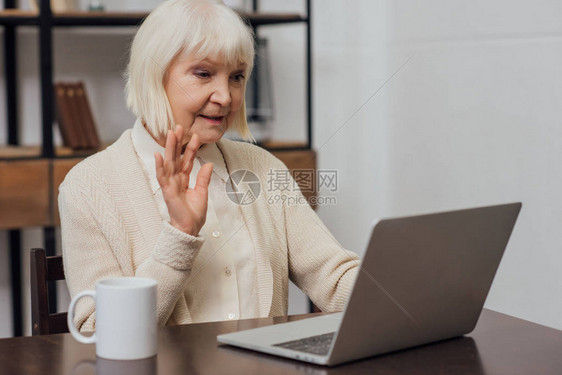 坐在计算机桌上的高级妇女在家里打视频电话图片