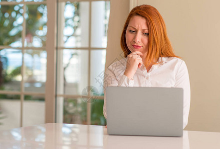 红头妇女在家里使用电脑笔记本电脑严重地面对问题图片