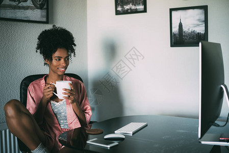 早晨在家用电脑和咖啡工作的黑妇女背景图片